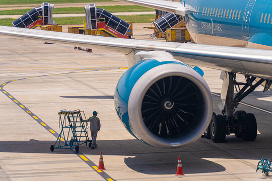 Ground crew worker near a commercial jet engine on the apron in Ho Chi Minh City