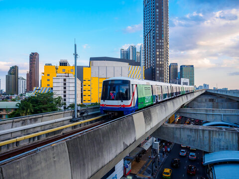 Bangkok, Thailand - July 8, 2026 :  The BTS Skytrain runs in and out of Ha Yaek Lat Phrao Station in the evening, offering views of office buildings and beautiful scenery. illustrative