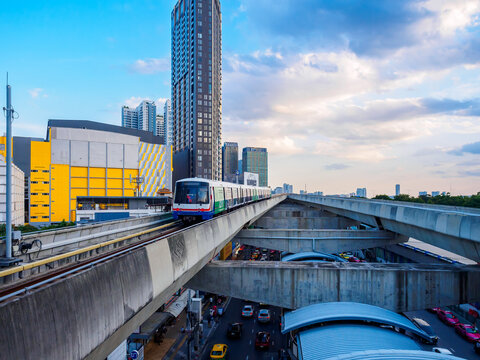 Bangkok, Thailand - July 8, 2026 :  The BTS Skytrain runs in and out of Ha Yaek Lat Phrao Station in the evening, offering views of office buildings and beautiful scenery. illustrative