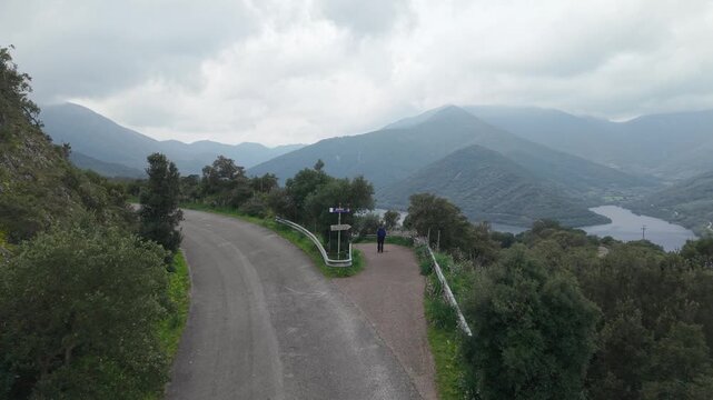 Hiker On A Mountain Road Overlooking Lago di Montimannu In Sardinia, Italy. Aerial Drone Shot