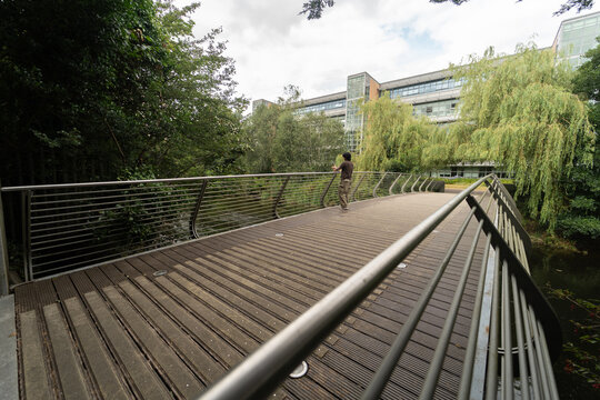 Person walking on modern wooden bridge by office building
