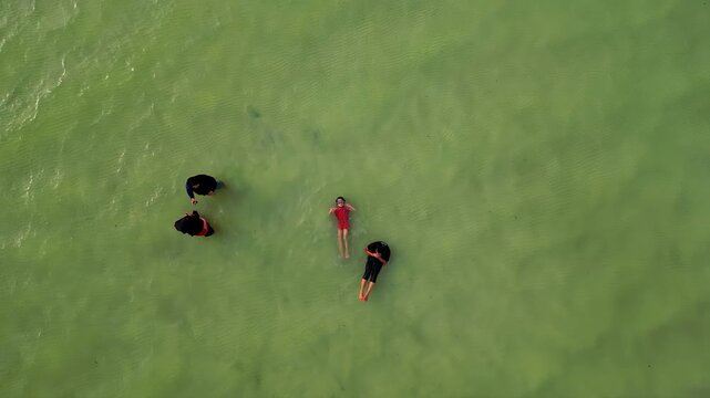 Siblings floating with family around in the sea.