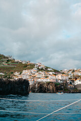 Obraz premium View of a coastal cliffside town from the water, Câmara de Lobos