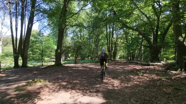 Drone tracking mountain biker through forest dramatic fast follow