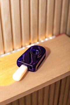 Blue popsicle shaped glass pipe on a wooden shelf