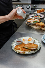 A chef seasons scrambled eggs in the restaurant kitchen. © Cavan