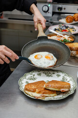 A female chef is preparing breakfasts in a restaurant. © Cavan
