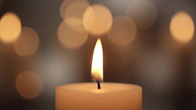 Single burning white candle with glowing warm bokeh background representing peace, hope, and memory