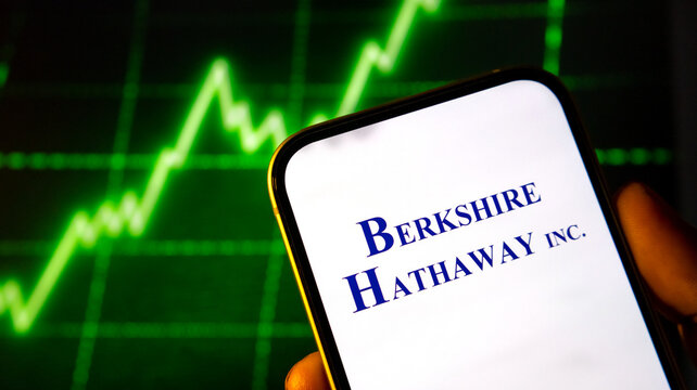 Berkshire hathaway logo displayed on smartphone screen with digital stock market chart background.