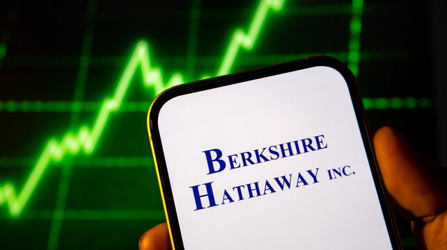 Berkshire hathaway logo displayed on smartphone screen with digital stock market chart background.