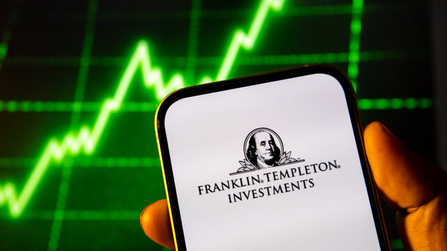 Franklin Templeton Investments logo displayed on smartphone screen with green stock market chart background.