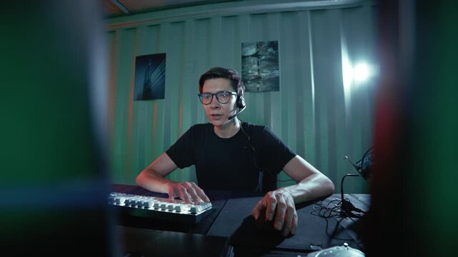 Male hacker programmer working on a computer in a dark room with green lights