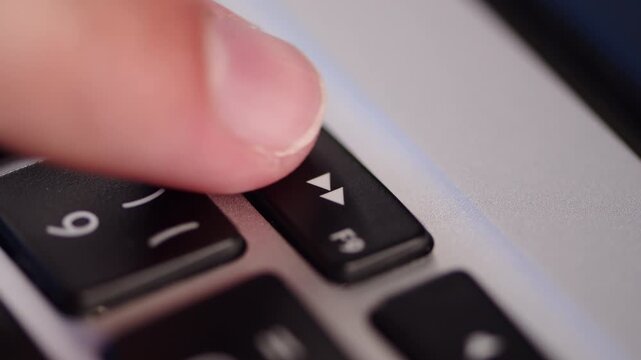 Extreme close up shot of a finger pressing the fast forward media control button on a keyboard. Finger pusihng laptop fast forward key.