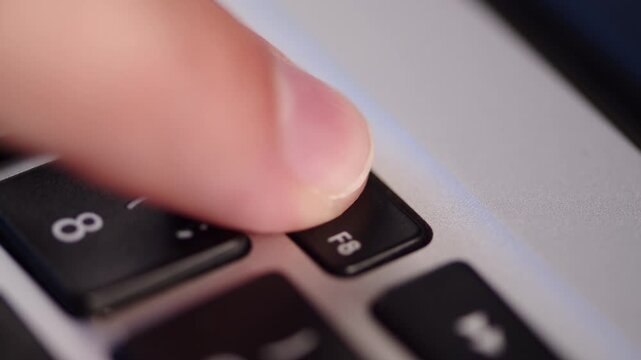 Laptop play and pause key close up. Pressing the play pause media control button on a silver laptop keyboard.