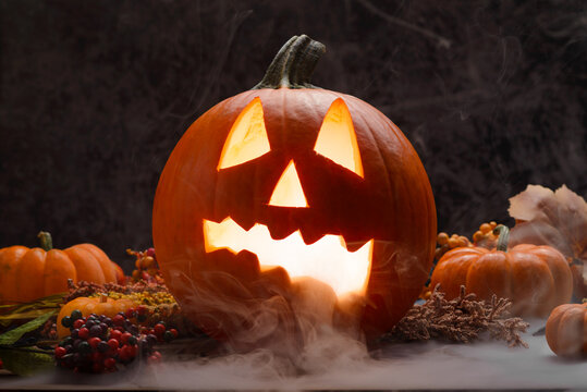 Glowing Traditional Carved Halloween Pumpkin With Fog and Autumn Decor