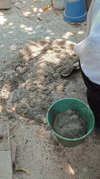 Mason Filling Green Plastic Bucket with Fresh Cement Mortar