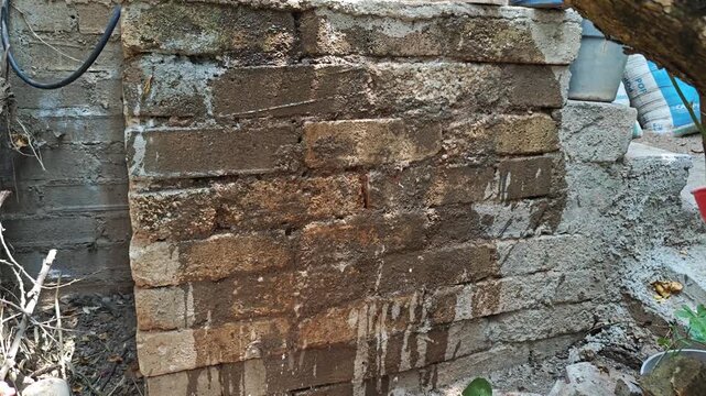 Mason Splashing Water onto Old Brick Wall Before Plastering