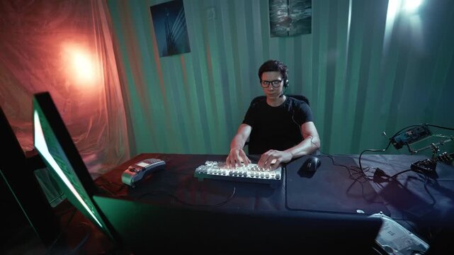Young male hacker successfully completing a cyberattack and feeling satisfied in his hideout