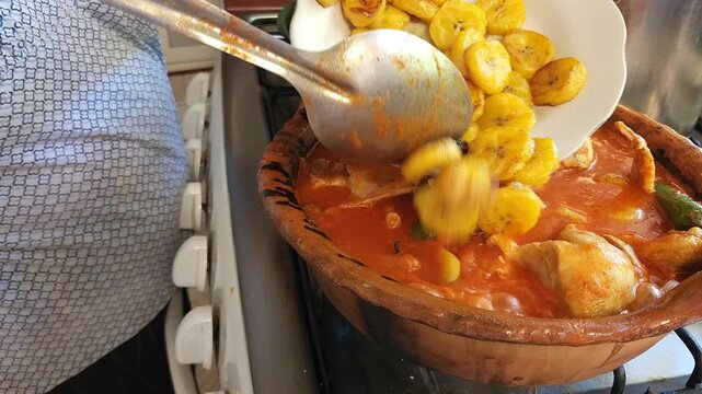 Cook Adding Fried Banana Slices to Traditional Chicken Stew