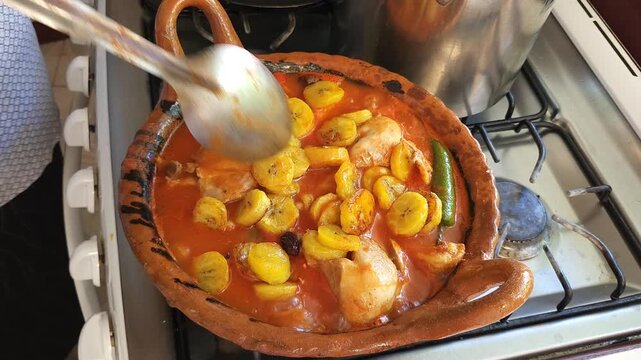 Cook Stirring Chicken Stew in Red Chili Sauce inside Clay Pot