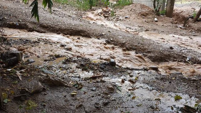 Muddy Streams of Dirty Water Merging on Dirt Road After Rainstorm