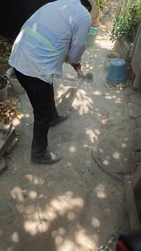 Mason Shoveling and Mixing Sand with Cement Mortar on Ground