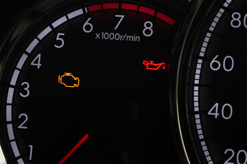 Fototapeta premium Close-up of car dashboard showing check engine and low oil pressure warning lights on tachometer