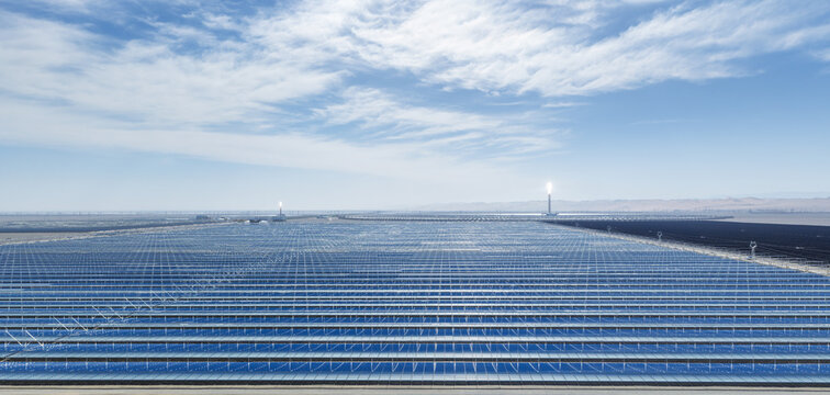 Aerial View of Concentrated Solar Power Station with Linear Fresnel Reflectors and Glowing Molten Salt Towers in Desert