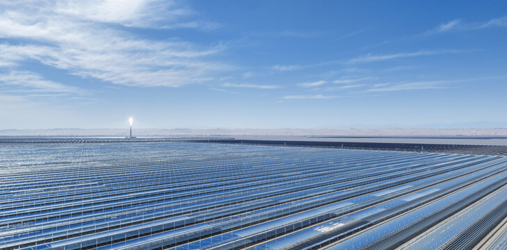 Aerial view of Linear Fresnel Reflector concentrated solar power station with distant glowing molten salt tower in desert