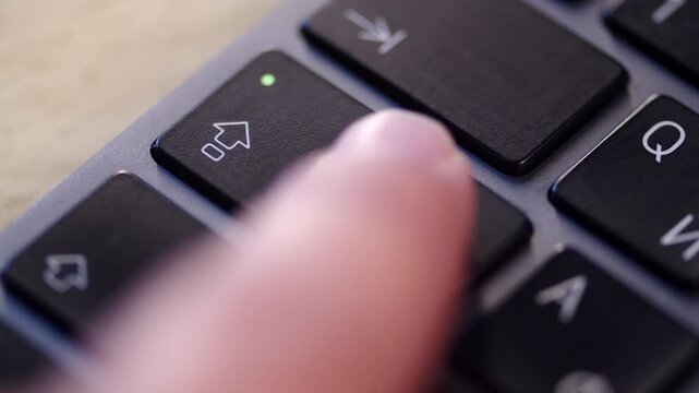 Extreme close up, pressing the Caps Lock key on a black keyboard. Pushing the caps lock button on a computer.