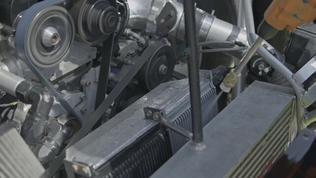 Action shot of a mechanic using an air gun to clean out debris from the cooling radiator and intercooler assembly of a modified race car.