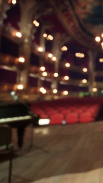 Musicians set up instruments on stage in a theater. Chairs fill the area in front. Soft lights illuminate the scene. The event is about to begin, creating anticipation in the room.