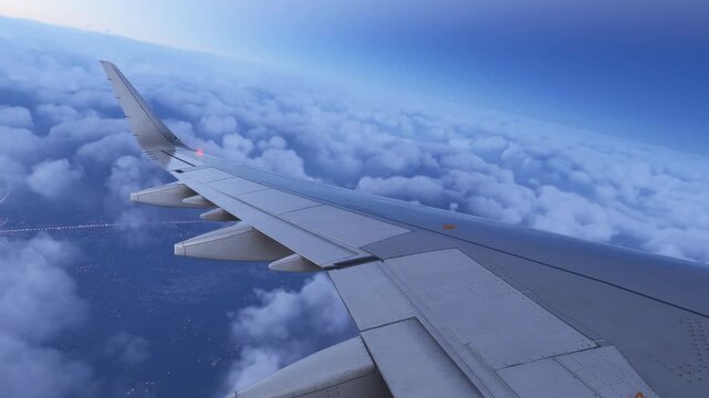 Airplane Wing Flying High Above Fluffy White Clouds in Blue Sky.