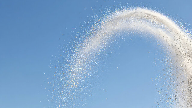 Dynamic Water Fountain Jet Spraying in a Curved Arc Against a Clear Blue Sky Background
