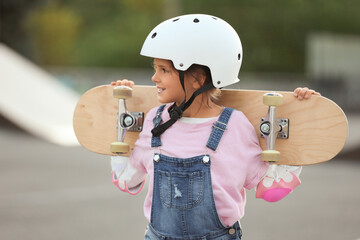 Cute little girl with skateboarding gear in park