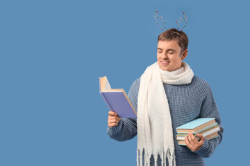 Fototapeta premium Young man with books on blue background. Christmas celebration