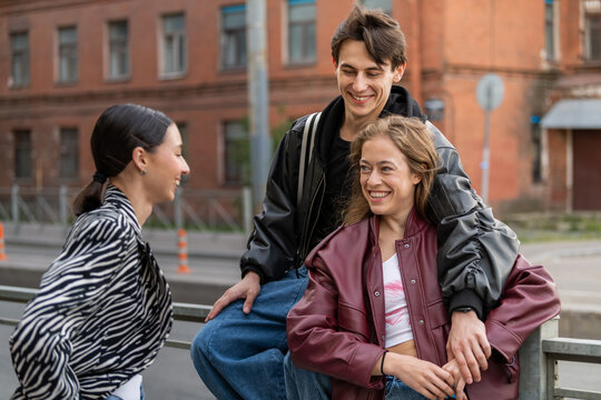 Three young friends laughing together on a city street