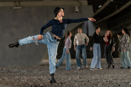 Stylish woman performing dance move in urban setting