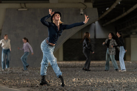 Expressive female dancer striking a pose under a bridge