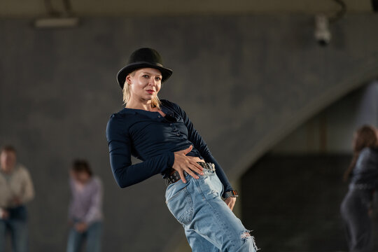 Stylish woman in a bowler hat strikes a dance pose
