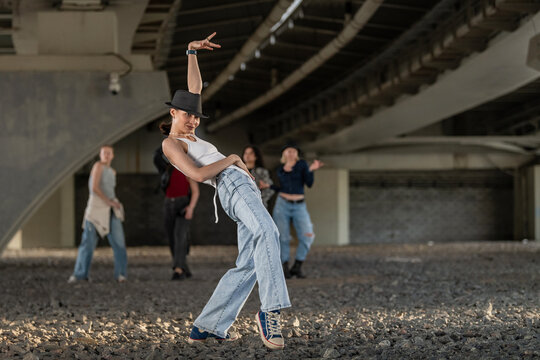 Female street dancer posing for camera under bridge