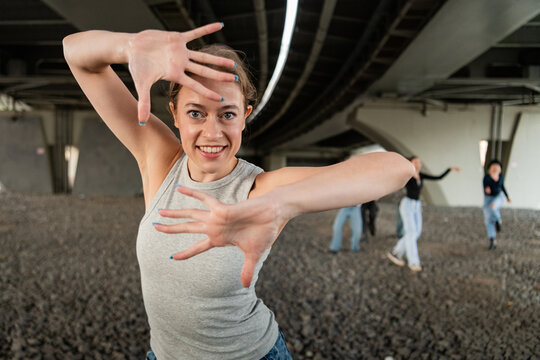 Woman smiles framing face with hands while dancing