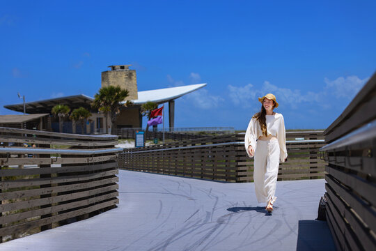 A young woman walks the boardwalk on the way to the beach.