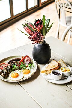 Hearty breakfast with protea flowers on table