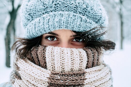 Woman with eyes peeking over a scarf in snow