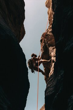 Adventurous man abseiling down a slot canyon