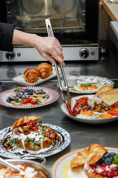 A female chef is preparing breakfasts in a restaurant.