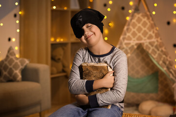 Fototapeta premium Cute boy dressed as pirate with adventure book at home in evening