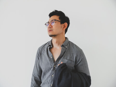 Thoughtful Asian Man in Glasses and Grey Shirt Looking Up Against Clean White Background