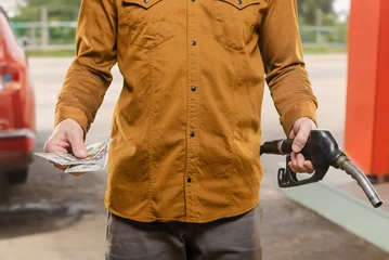 Closeup photo of man refueling car at gas station for cash Comparing fuel purchases with personal budget expectations after filling the vehicle © Denys Kurbatov
